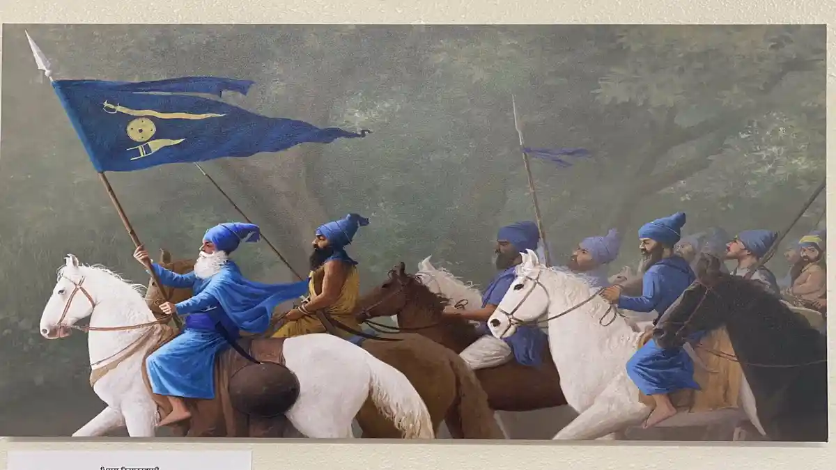Nishanwalia Misl warriors riding on horses with the blue Khalsa flag leading the march.