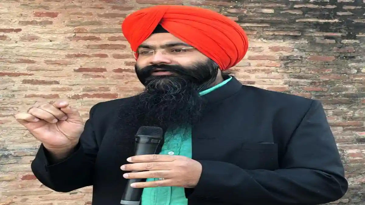 Harpreet Singh Makhu speaking with mic and red turban.