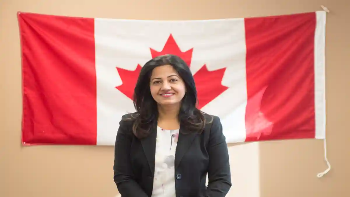 Sonia Sidhu in a professional setting with awards in the background.